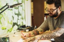 Man with tattoos drawing — Stock Photo