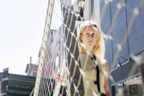 Businesswoman standing at metal fence — Stock Photo