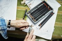Frau spitzt Bleistifte mit Bastelmesser — Stockfoto