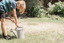 Boy filling watering can — Stock Photo