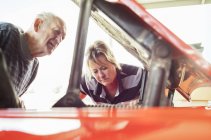 Woman and senior man repairing a car — Stock Photo