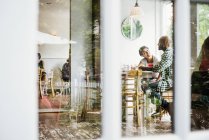 Personas sentadas en mesas en la cafetería - foto de stock