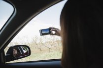 Woman in a car taking a picture — Stock Photo