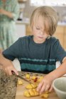 Мальчик режет фрукты — стоковое фото