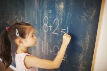 Girl writing in chalk on a chalkboard — Stock Photo