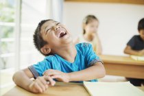 Junge sitzt im Klassenzimmer und lacht. — Stockfoto