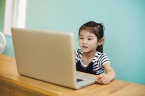 Chica sentada en un ordenador portátil - foto de stock