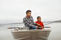 Два хлопчики сидять на риболовлі з човна . — стокове фото