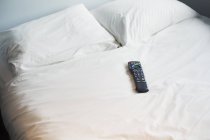 Remote control lying on bed — Stock Photo