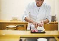 Koch präsentiert einen frischen Teller Sushi. — Stockfoto