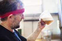 Brewer brewing beer and examining it. — Stock Photo