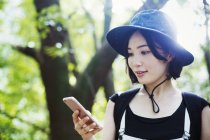 Mujer usando un teléfono móvil en el bosque - foto de stock