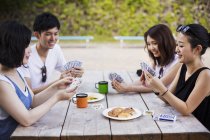 Mujeres y un hombre jugando a las cartas . - foto de stock
