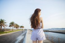 Woman standing by a road on the coast. — Stock Photo