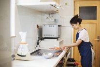 Mulher em uma cozinha preparando uma refeição . — Fotografia de Stock