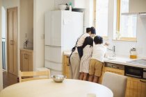 Madre e bambini al lavandino in cucina . — Foto stock