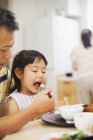 Man feeding daughter at a meal. — Stock Photo