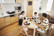 Família de dois adultos e duas crianças comendo — Fotografia de Stock