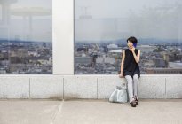 Женщина у окна с видом на город — стоковое фото
