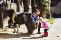 Woman showing a toddler a pony's shoe. — Stock Photo