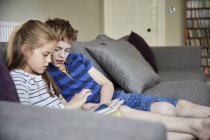 Kinder sitzen und teilen sich ein digitales Tablet — Stockfoto