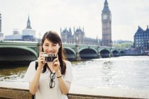 Woman smiling and holding camera — Stock Photo