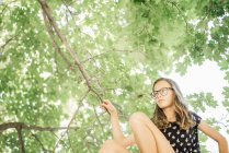 Jovem sentada na árvore alta — Fotografia de Stock