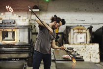 Glassblower holding of molten glass — Stock Photo