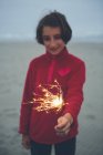 Girl holding lighted sparkler — Stock Photo