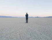 Hombre de pie en vasta playa del desierto - foto de stock