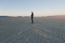 Hombre de pie en vasta playa del desierto - foto de stock