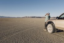 Людина дивиться через бінокль в пустелі — стокове фото
