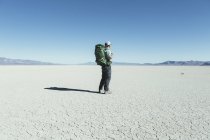 Male backpacker hiking in vast desert — Stock Photo