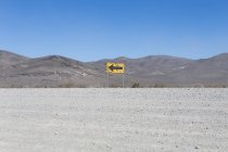 Bullet riddled arrow sign in desert — Stock Photo