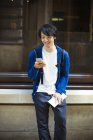 Молодой японский мужчина с помощью смартфона — стоковое фото