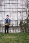 Young man standing with basket of plants — Stock Photo