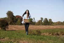 Mujer joven caminando con cesta de plantas - foto de stock