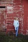 Young woman leaning against barn — Stock Photo