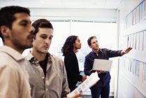 Woman and three men in office looking at display — Stock Photo
