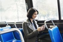Жінка сидить на поїзді з мобільним телефоном — стокове фото