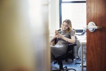 Жінка сидить і використовує смартфон — стокове фото