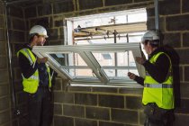 Two builders fitting window frame. — Stock Photo