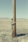 Man with his arms around wooden pole — Stock Photo