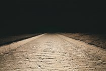 Грязная дорога в пустыне освещена автомобильными фарами — стоковое фото