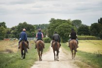 Riders on thoroughbred horses riding along path — Stock Photo
