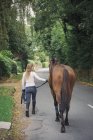 Woman and horse walking along road — Stock Photo