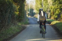 Ciclista pedaleando por la carretera del país - foto de stock