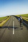 Ciclista pedalando ao longo da estrada país — Fotografia de Stock