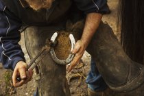 Farrier fitting horseshoe to horse hop — стоковое фото