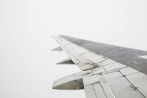 Aeroplane wing in flight on grey sky — Stock Photo